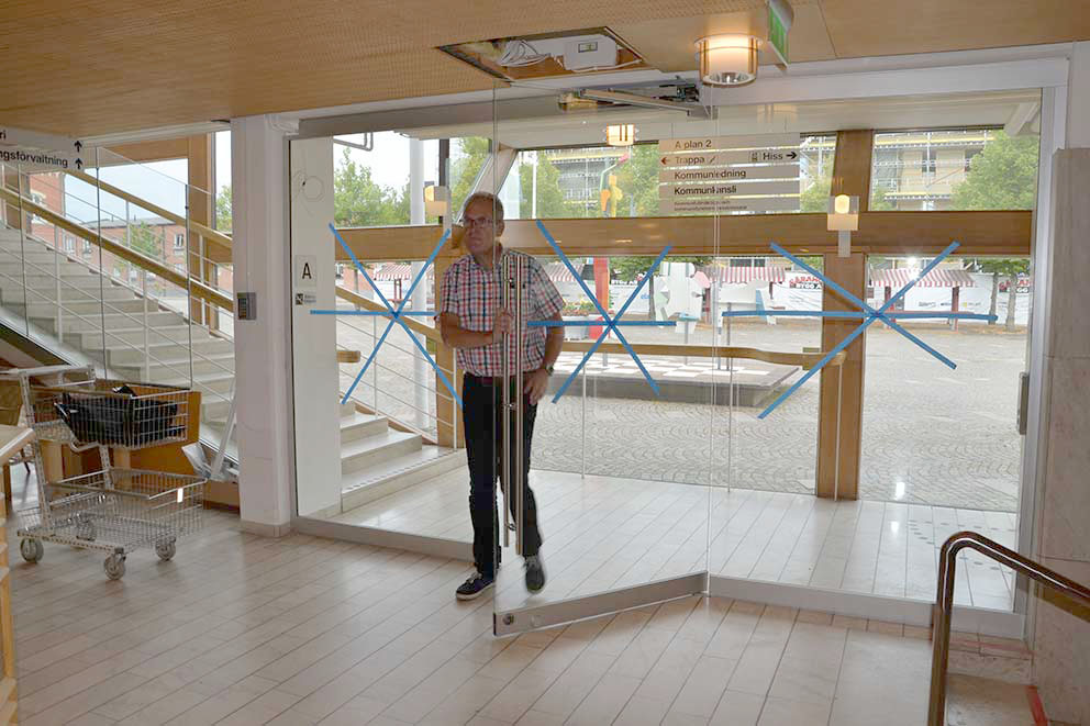 Kommunchefen Ulf Svensson passerar här de nya glasdörrarna som ska skydda personalen på kommunkansliet.